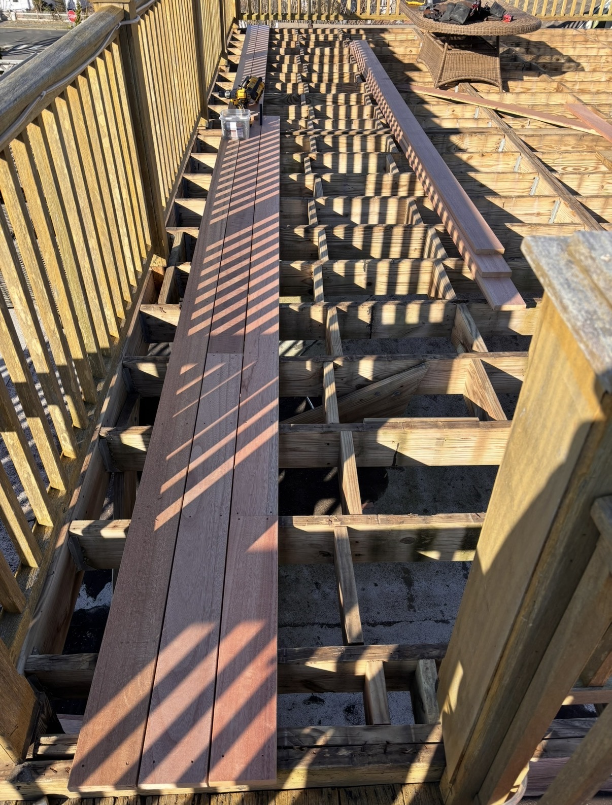 First mahogany deck boards being laid over fresh joists in the sun